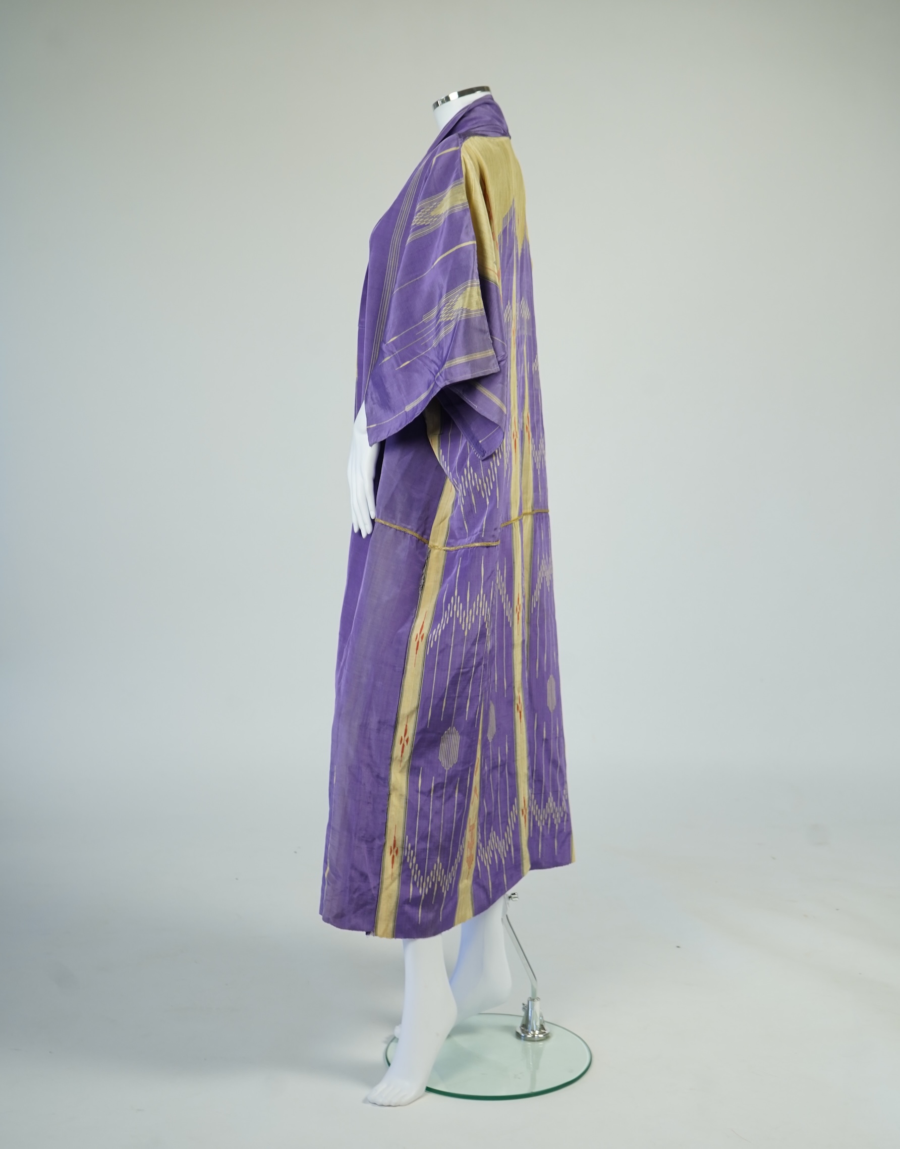 An early 20th century Syrian hand woven silk coat. Woven with stripes and geometric shapes in purple and yellow and red., 130 cm long. Condition - good, colours and fabric strong.